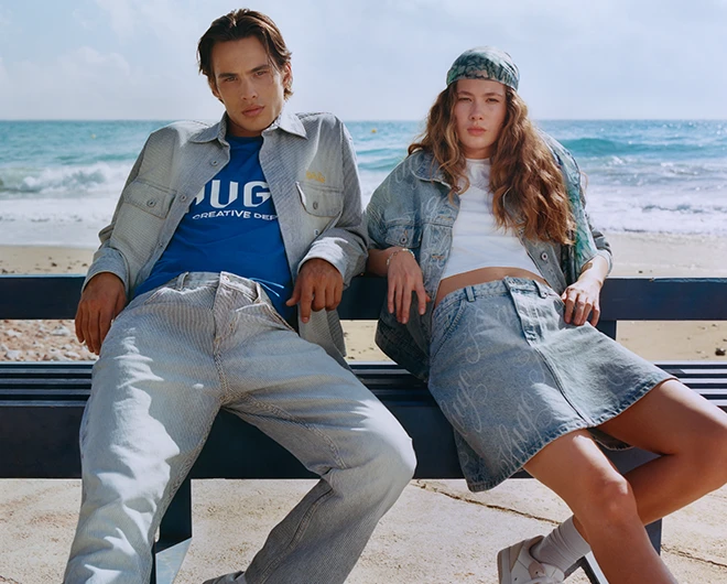 A young man and young woman on a bench on the beach in jeans outfits (photo)